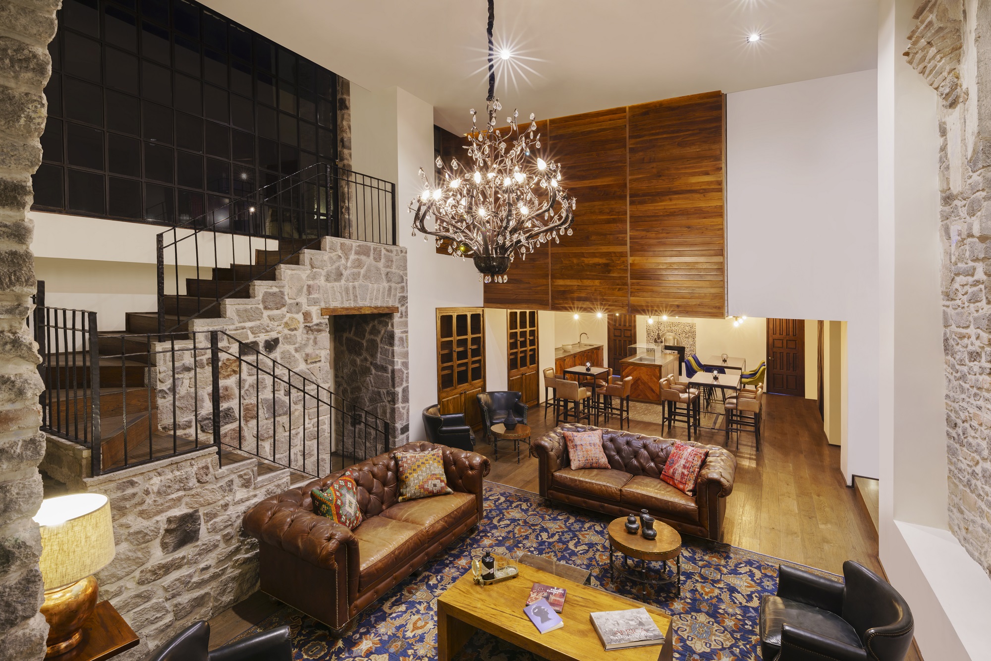 Luxurious Banyan Tree Puebla lounge; Bar Los Lavaderos plush sofas under elegant chandelier; stone walls and staircase.